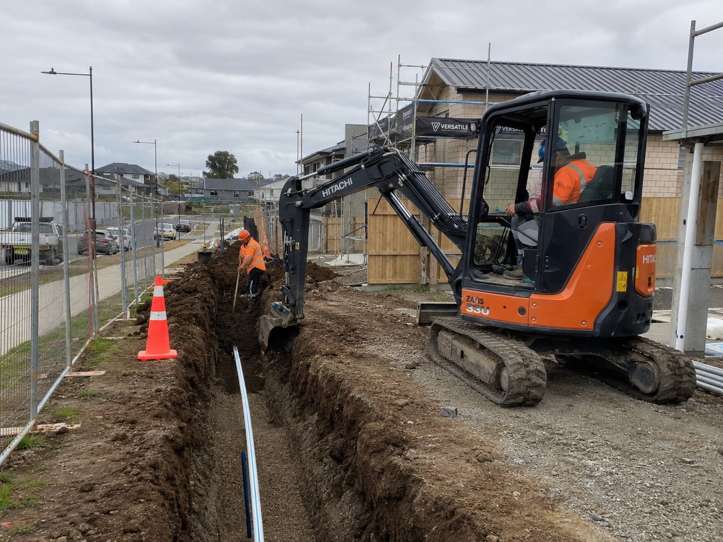 Excavator laying drainage pipe at a new build construction site in Hamilton