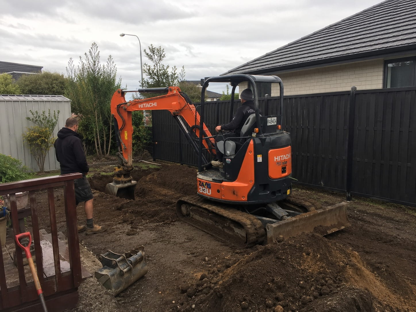 Excavator digging a drainage trench in a Hamilton backyard